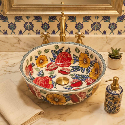 Decorative floral-patterned ceramic sink with gold fixtures on a marble countertop.