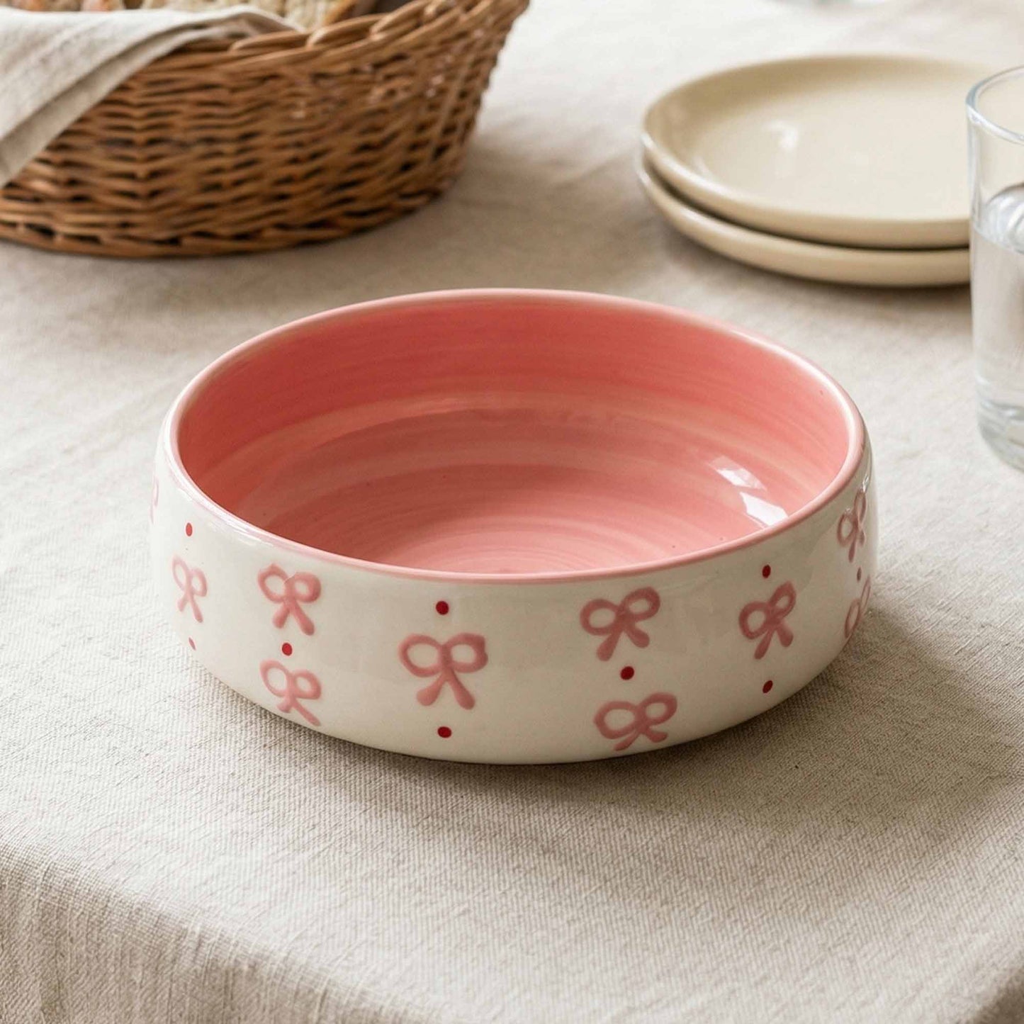 Pink ceramic bowl with bow pattern on a beige surface