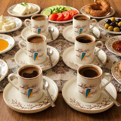 Café setting with coffee cups, plates, and snacks on a patterned tablecloth.