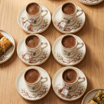 Café au lait served in decorative cups with saucers on a wooden table.