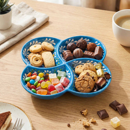 Blue divided tray with cookies, candies, and chocolates on a wooden table.