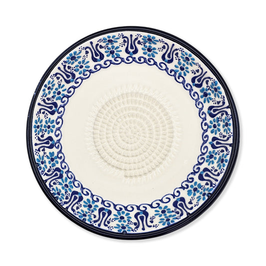 Decorative garlic grater plate with blue floral pattern on a white background