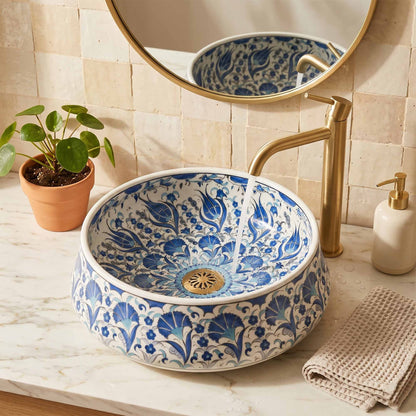 Decorative blue and white floral-patterned sink with a gold faucet in a bathroom setting.