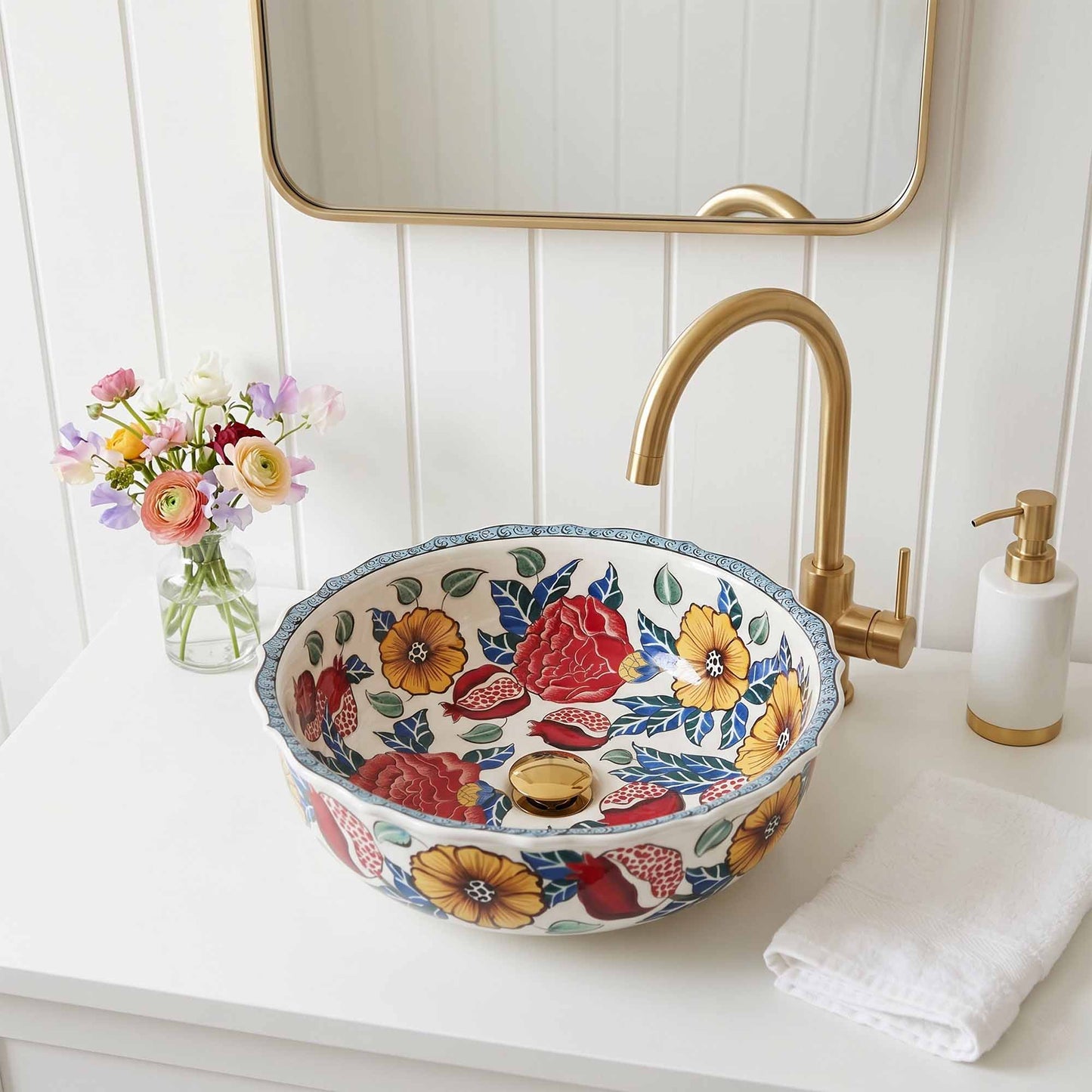 Decorative floral ceramic sink with gold faucet on a white vanity