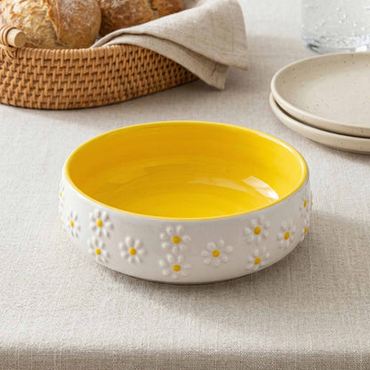 Yellow ceramic bowl with floral patterns on a beige surface