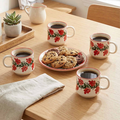 Four floral mugs with coffee and cookies on a wooden table