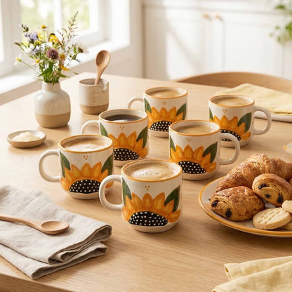 Sunflower-themed mugs on a table with pastries and flowers