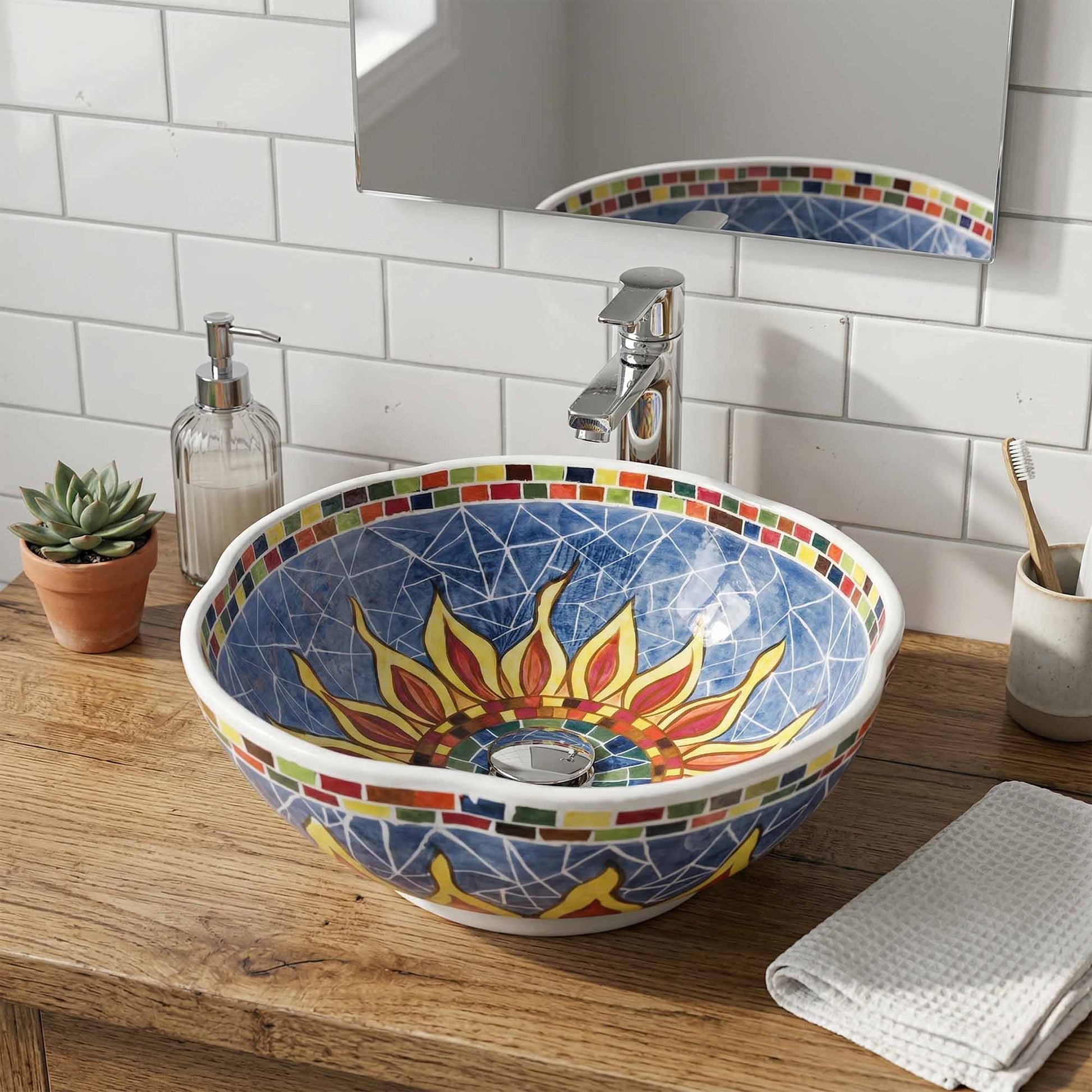 Colorful mosaic ceramic sink with sun design on a wooden countertop in a bathroom.
