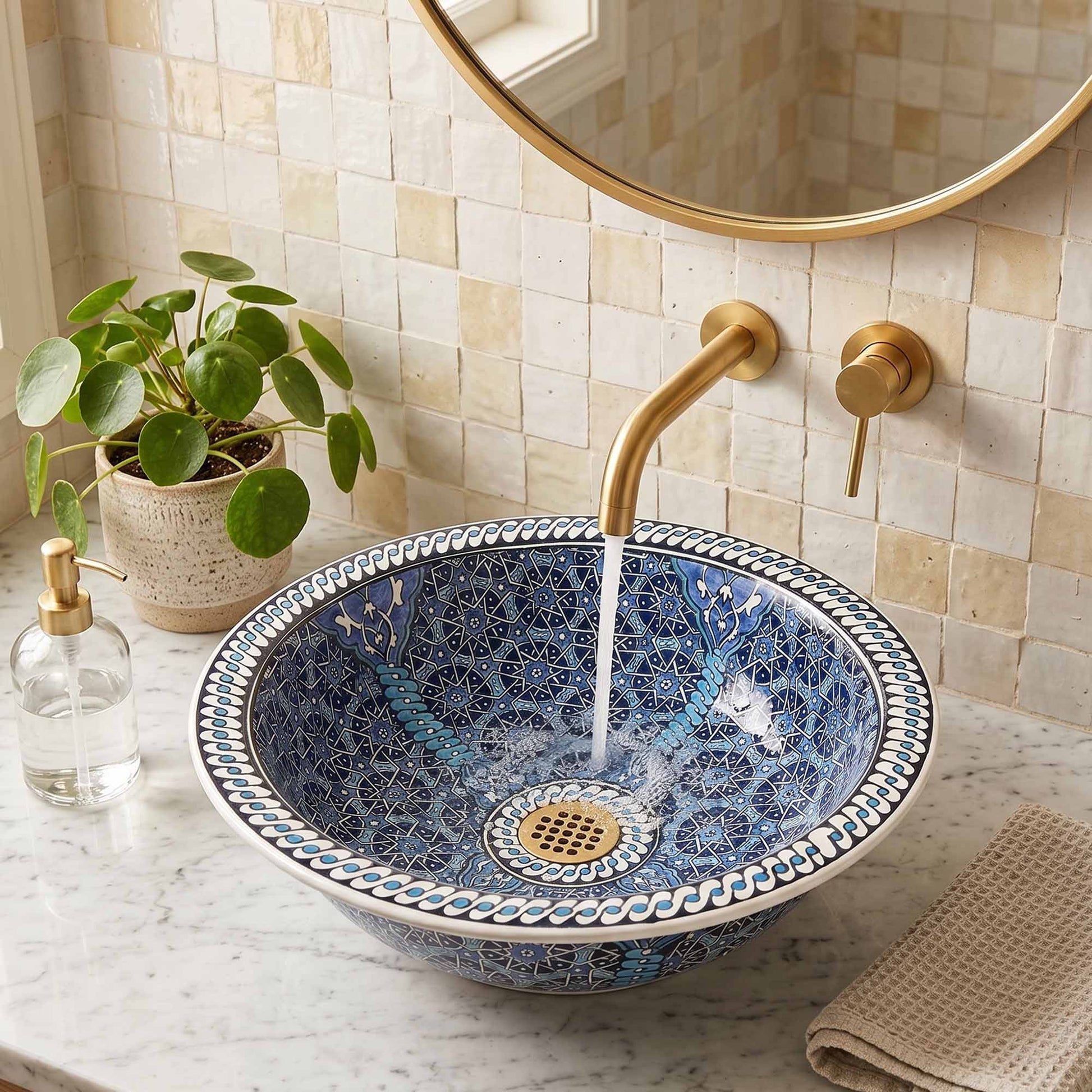 Decorative blue and white sink with gold fixtures in a bathroom setting.