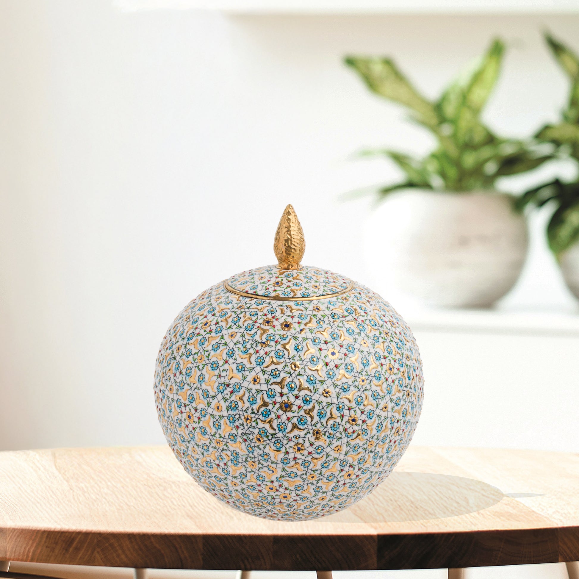 Hand-painted Floral Globe ceramic jar with blue blossoms and golden vines. Spherical artisan design with gold finial, perfect for décor or luxury gifting.