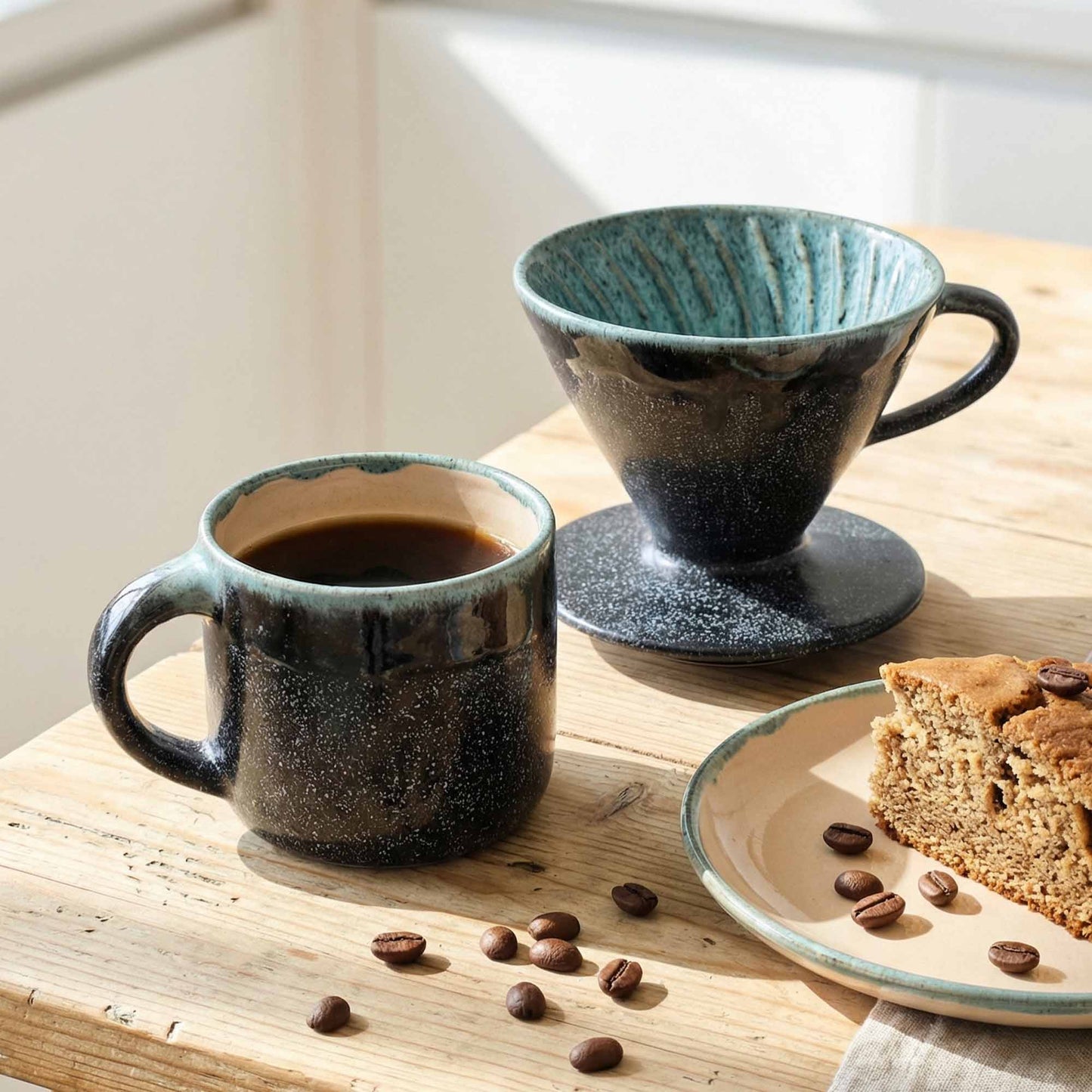 Two ceramic mugs with coffee and a slice of cake on a wooden table.
