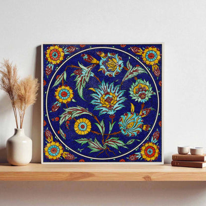 Decorative floral ceramic tile on a wall with a vase and books below.