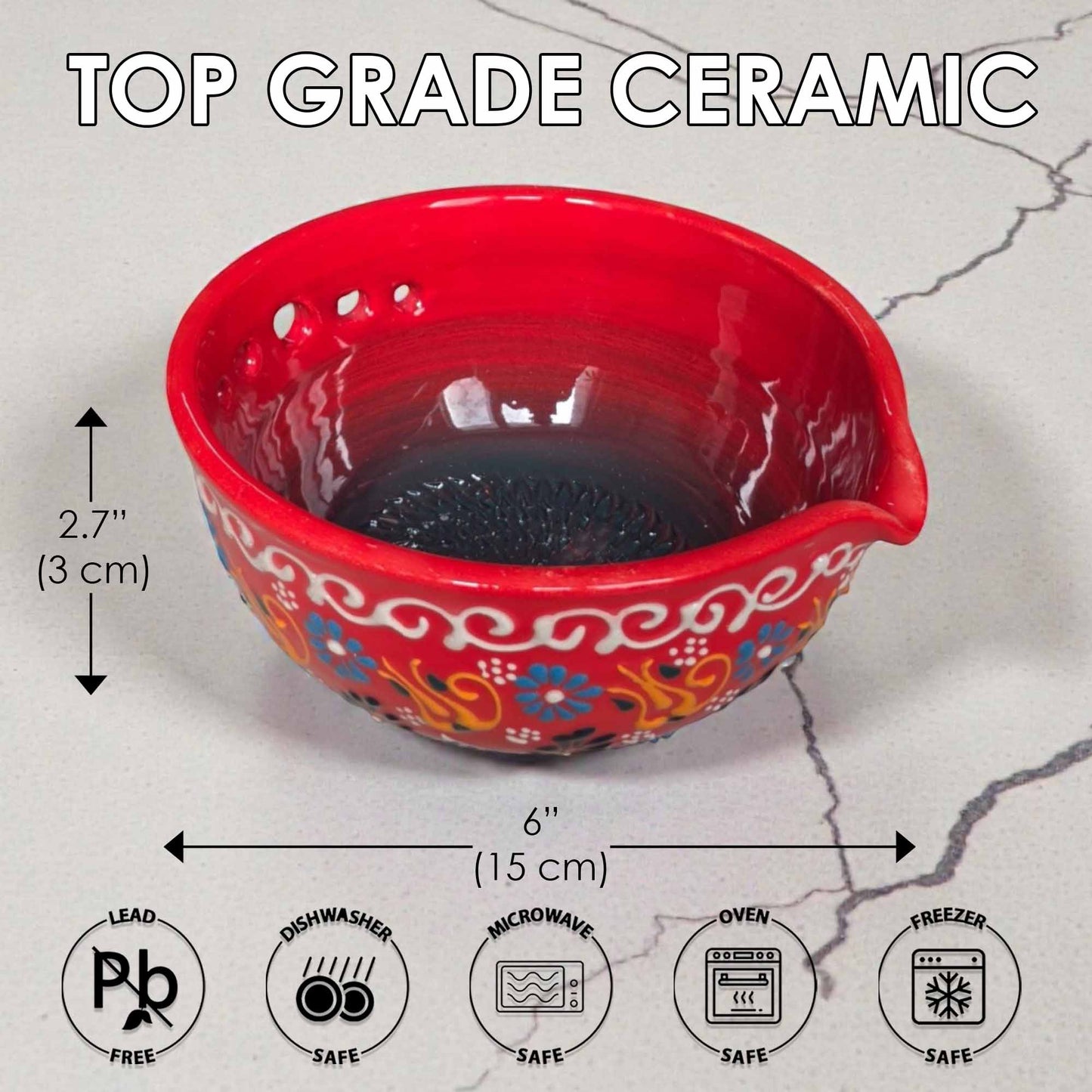 Red ceramic herb stripping bowl with floral patterns and measurements on a gray surface