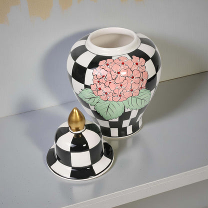 Decorative jar with black and white checkered pattern and floral design on a gray surface.
