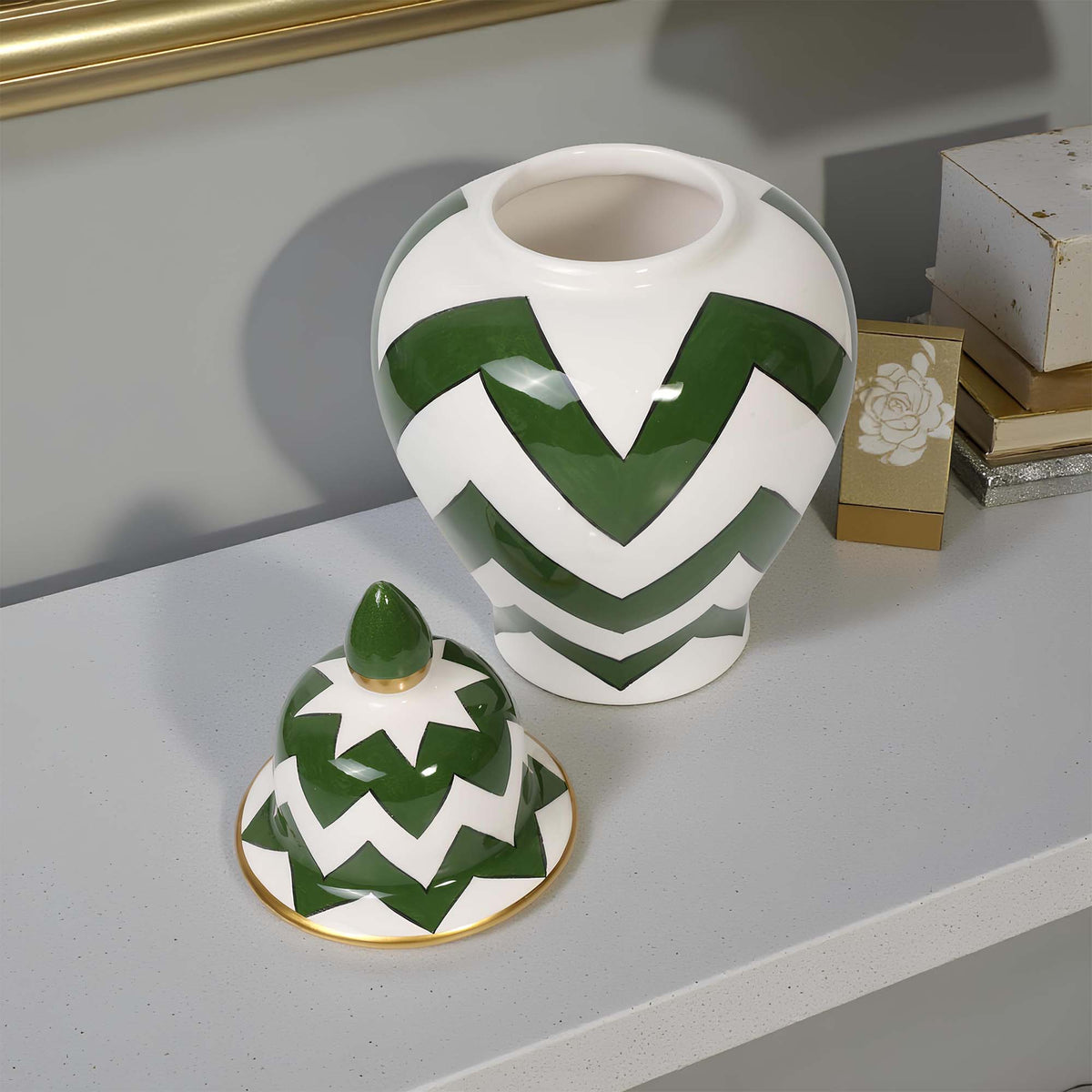 Green and white zigzag patterned jar and lid on a reflective surface with a gold frame in the background.
