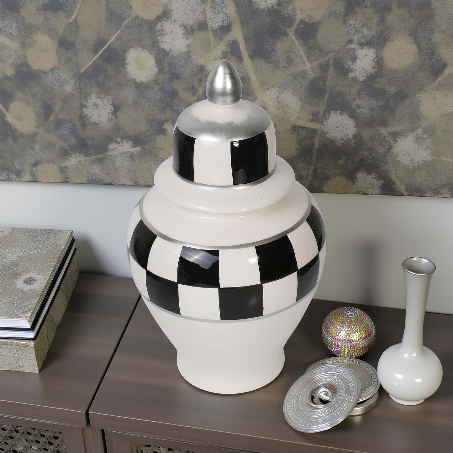 Decorative jar with checkered pattern on a wooden surface with a floral wallpaper background