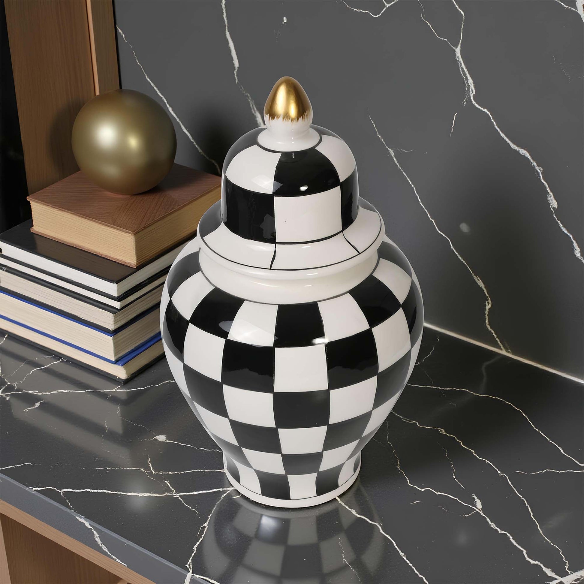 Black and white checkered vase with a gold top on a marble surface