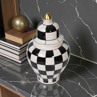 Black and white checkered vase with a gold top on a marble surface