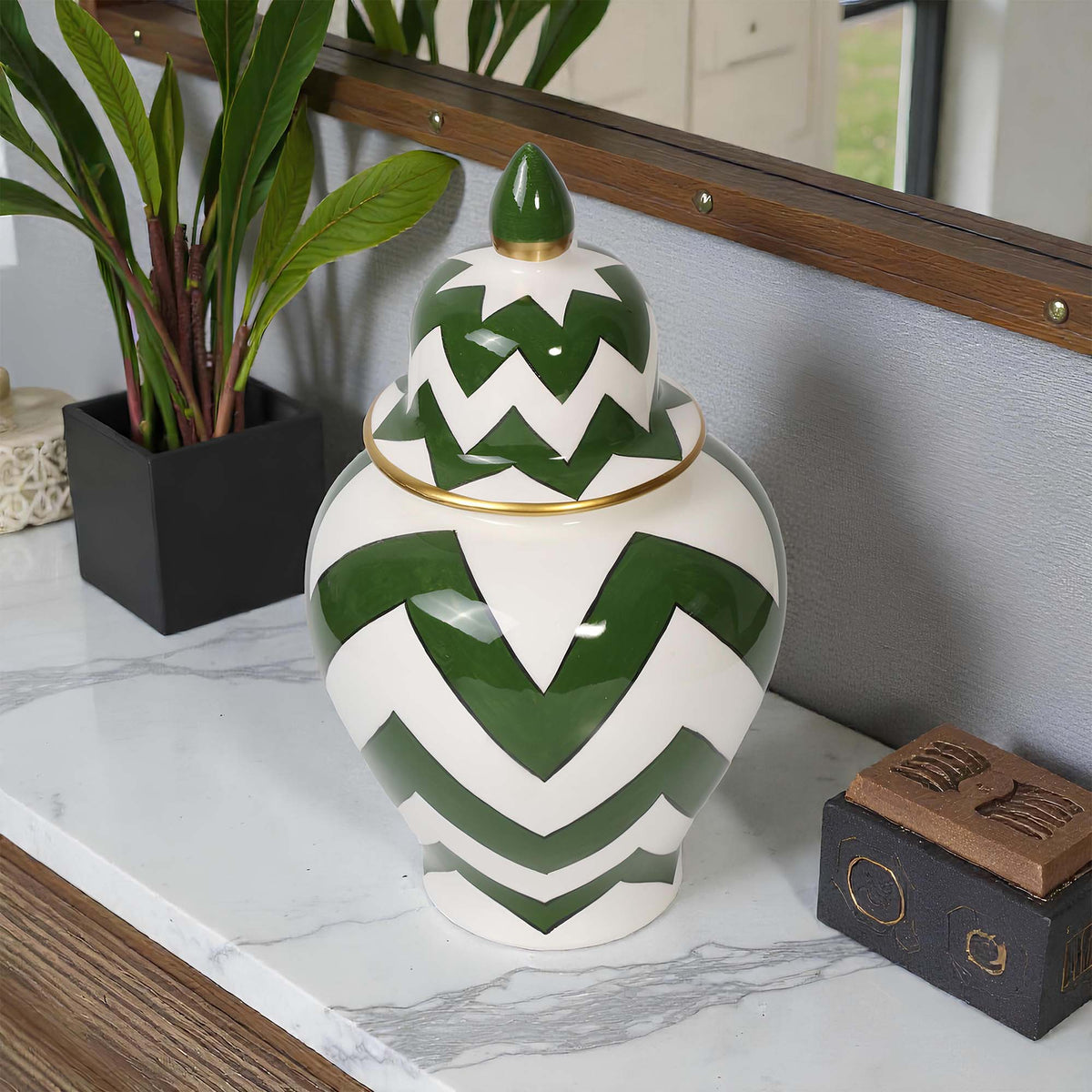 Decorative ceramic jar with green and white chevron pattern on a marble surface.