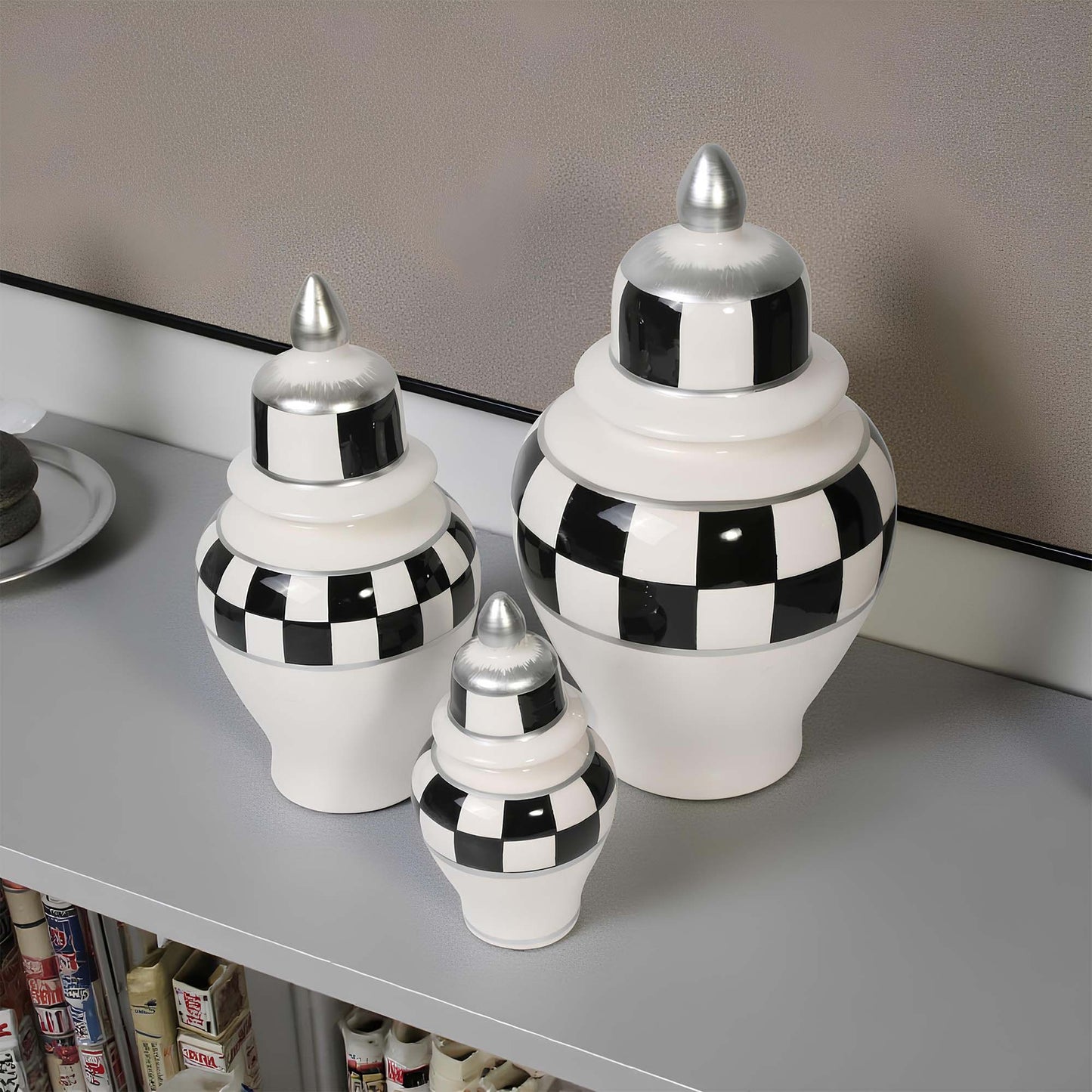 Set of three decorative jars with black and white checkered pattern on a shelf.