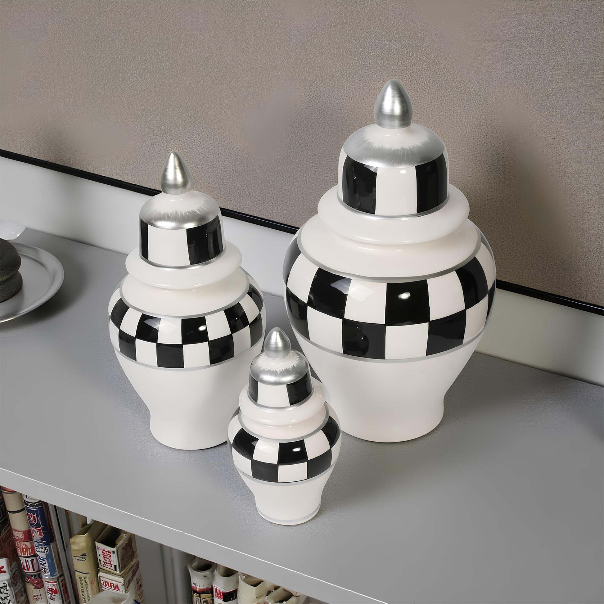 Set of three decorative jars with black and white checkered pattern on a shelf.