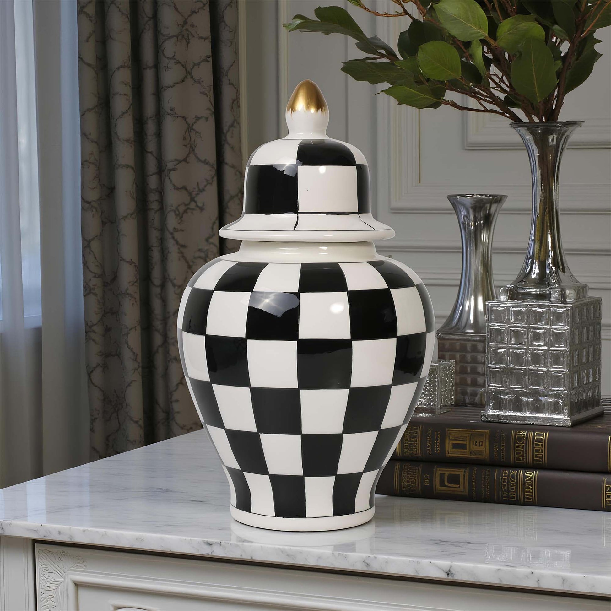 Black and white checkered vase on a marble surface with decorative books and vases in the background.
