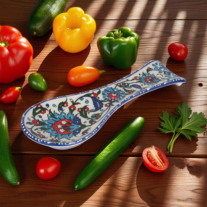 Colorful ceramic spoon rest on a wooden surface with various vegetables around it.