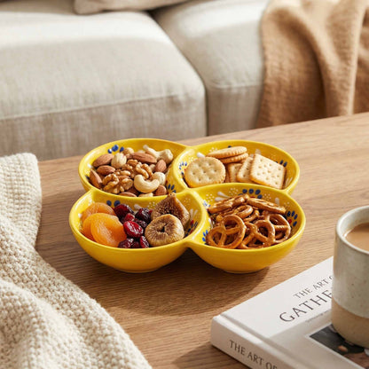 Yellow divided bowl with snacks on a wooden table with a book and mug in the background