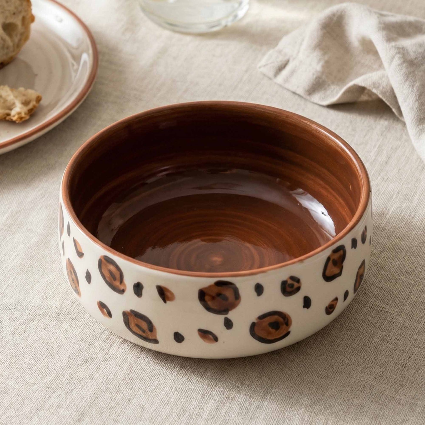 Ceramic bowl with brown and black pattern on a beige surface