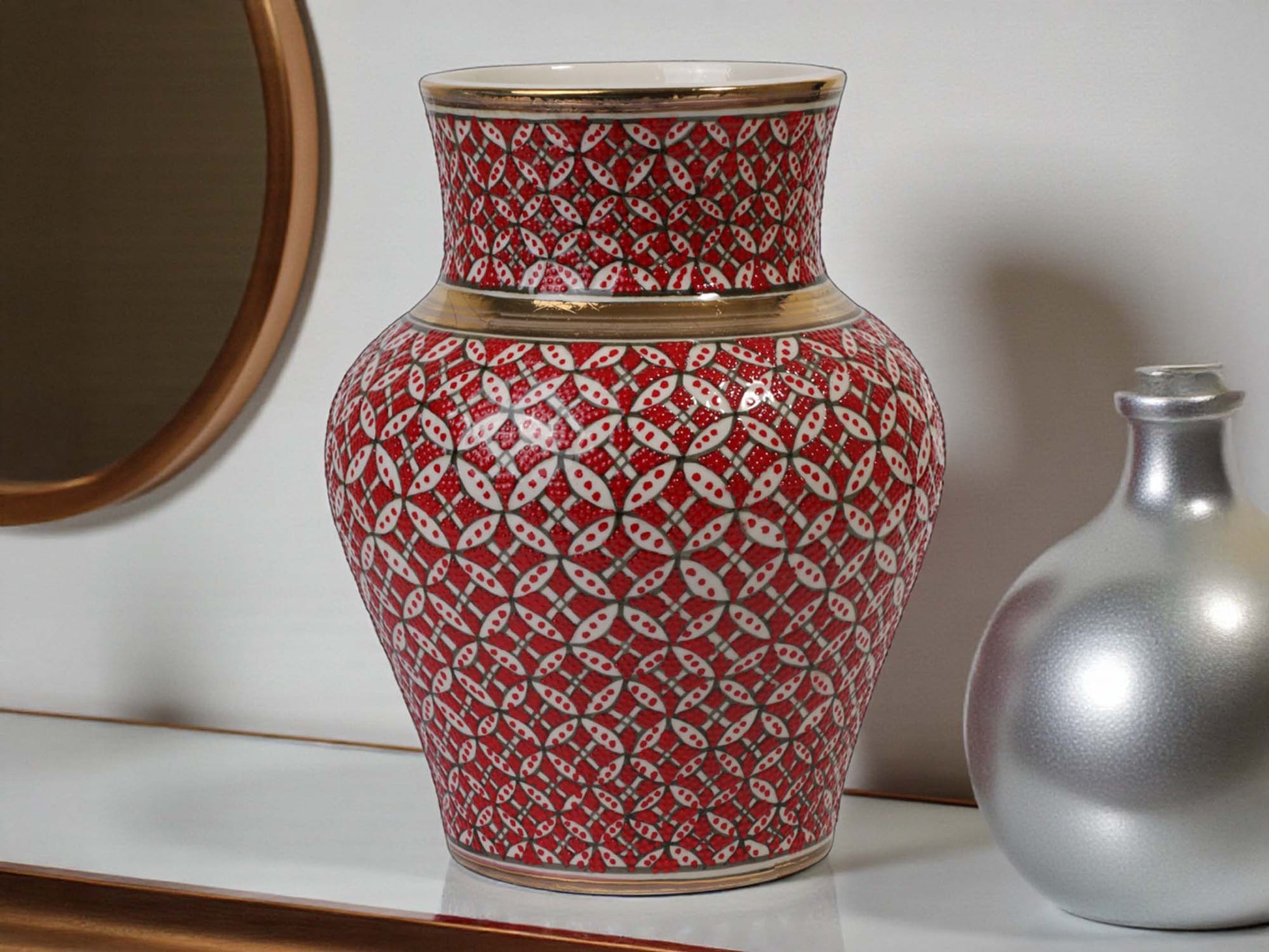 Decorative vase with red and white pattern on a shelf