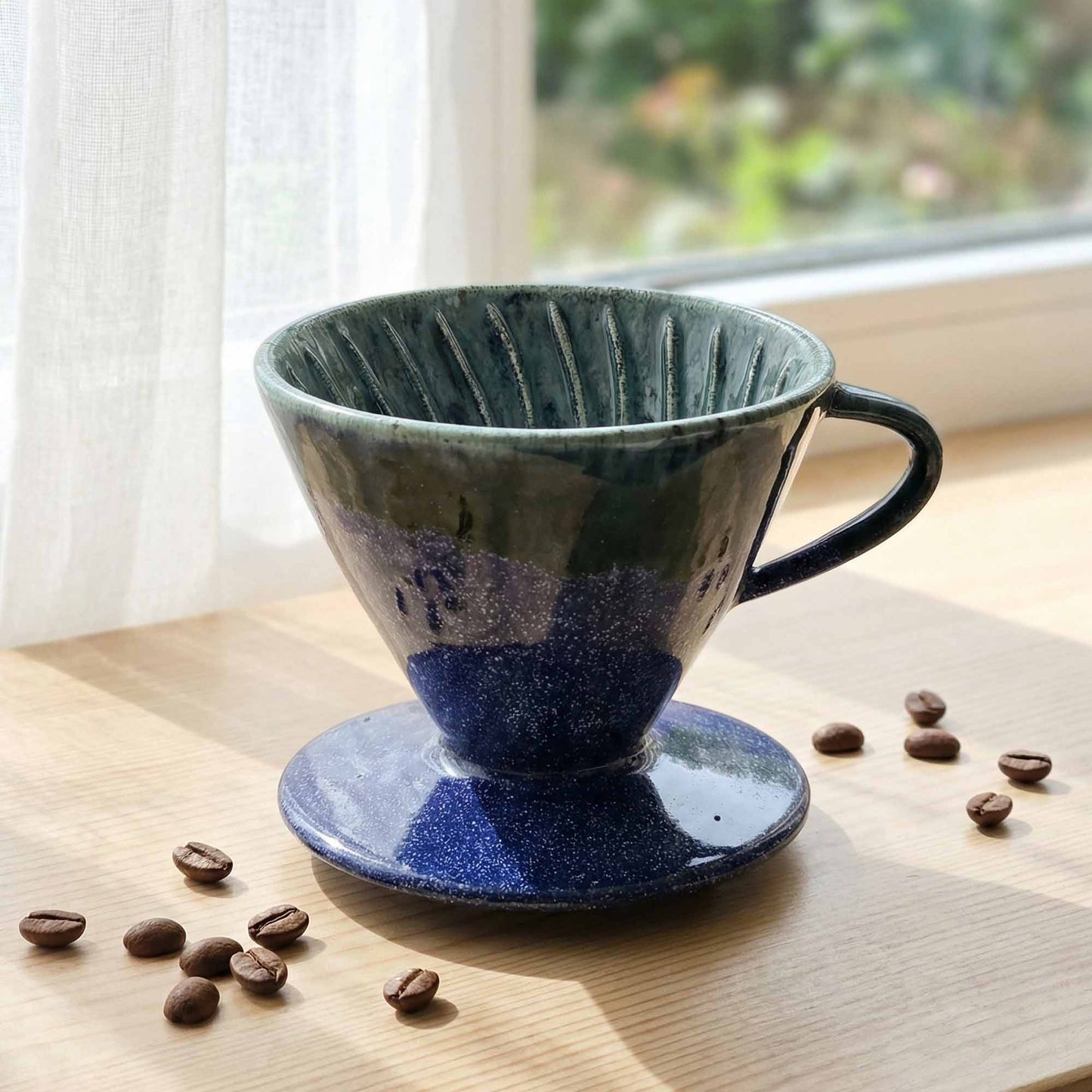 Blue ceramic coffee dripper on a wooden surface with scattered coffee beans.