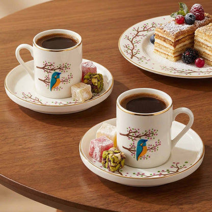 Two cups of coffee with saucers and pastries on a wooden table