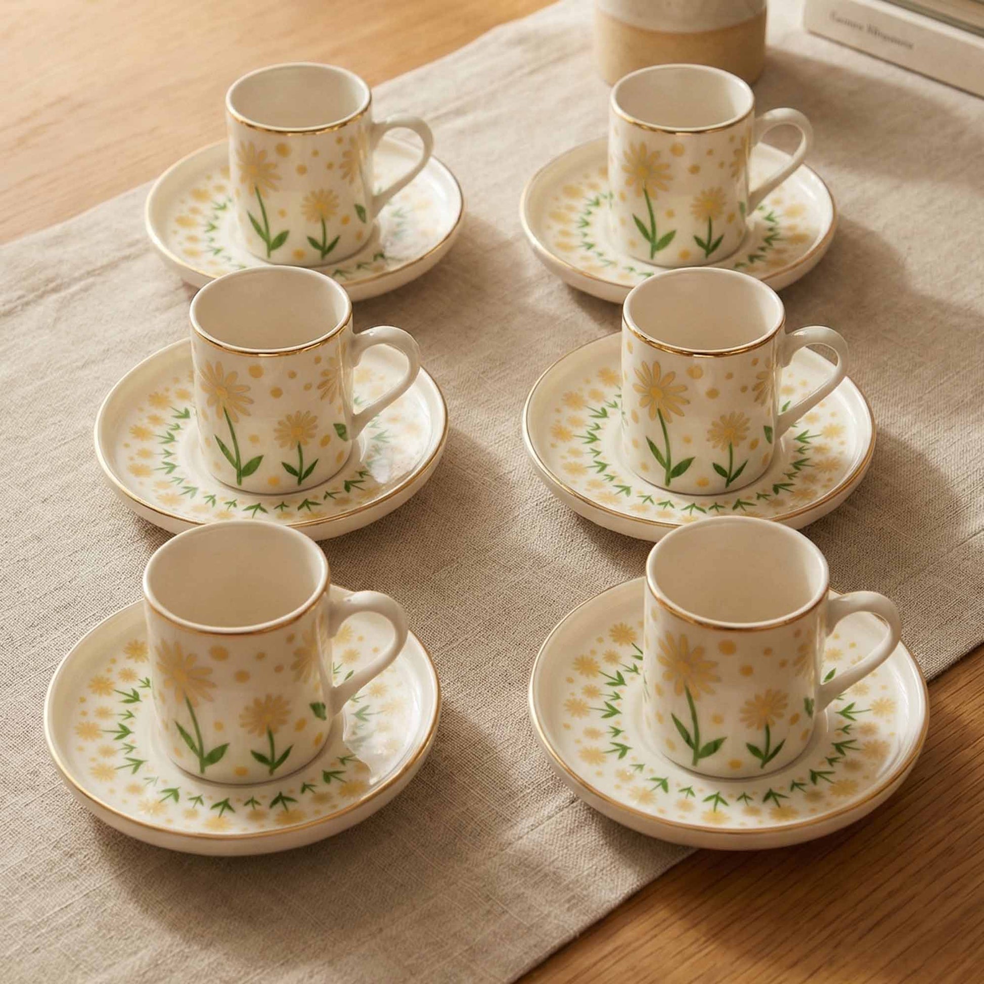 Set of six floral porcelain cups and saucers on a textured surface.