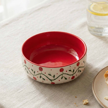 Red ceramic bowl with floral design on a light fabric surface