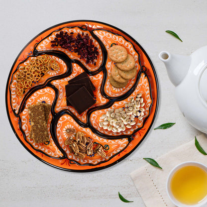 Decorative snack serving tray set with various snacks on a white surface with a teapot and cup.