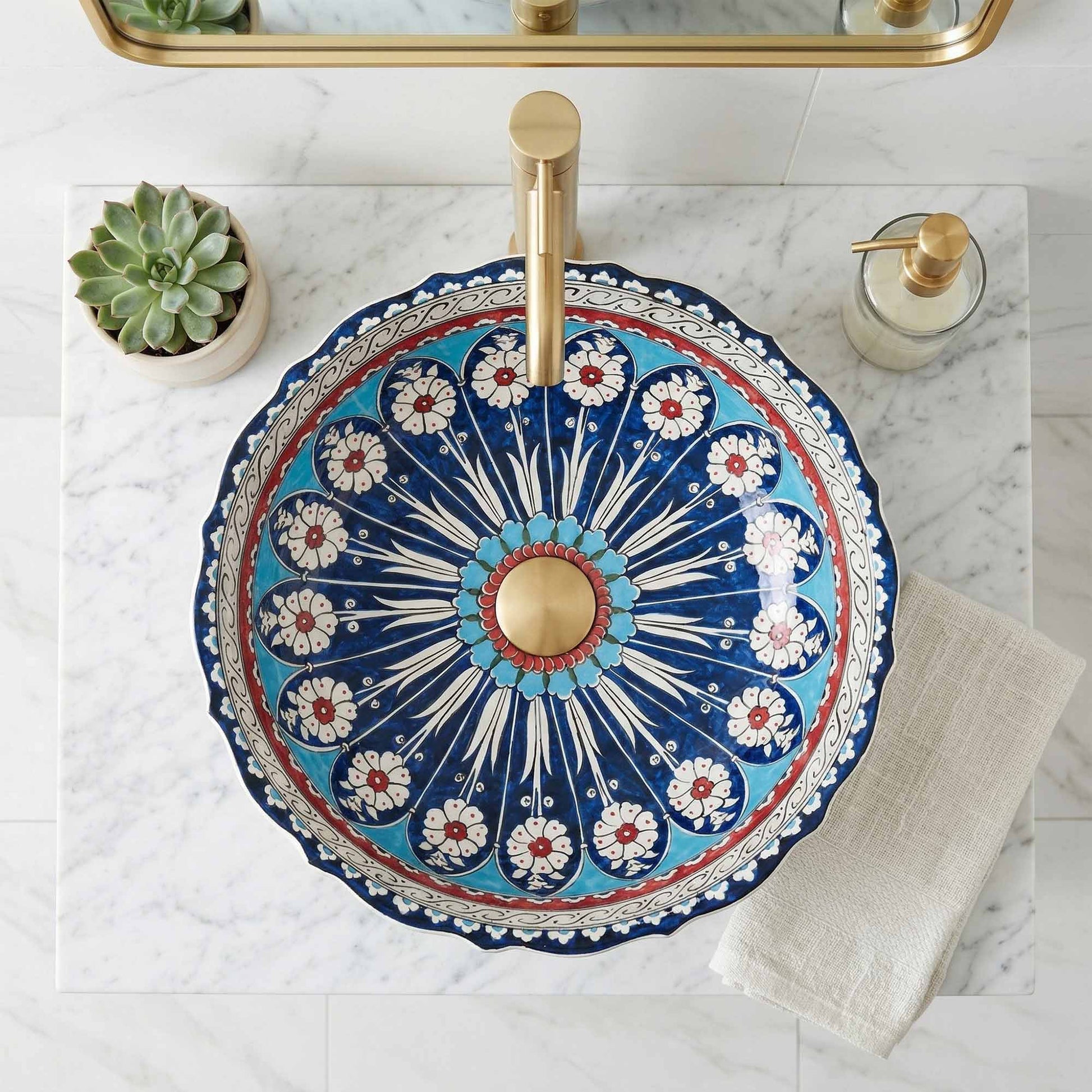 Decorative ceramic sink with floral pattern and gold faucet on marble countertop
