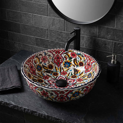 Decorative ceramic sink with floral patterns on a dark stone countertop.