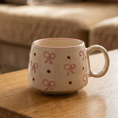 Ceramic mug with bow and dot pattern on a wooden surface