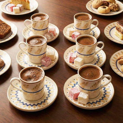 Café au lait served in patterned cups and saucers with pastries on a wooden table.