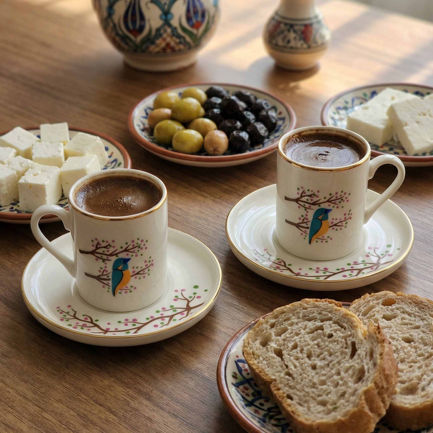 Two cups of coffee with saucers on a wooden table with bread and pastries.