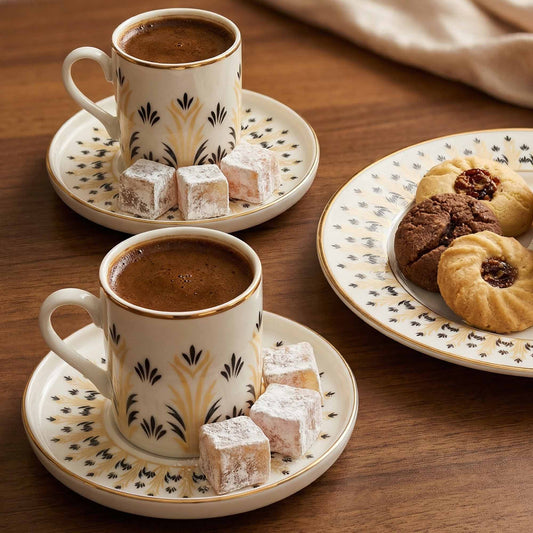Two cups of coffee with pastries and cookies on a wooden table