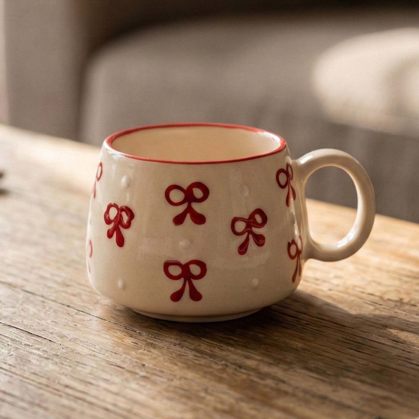 White mug with red bow patterns on a wooden surface