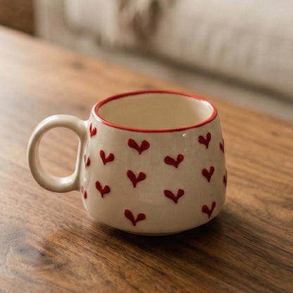 White mug with red heart patterns on a wooden surface