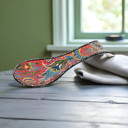 Colorful decorative spoon rest on a wooden surface with a window in the background
