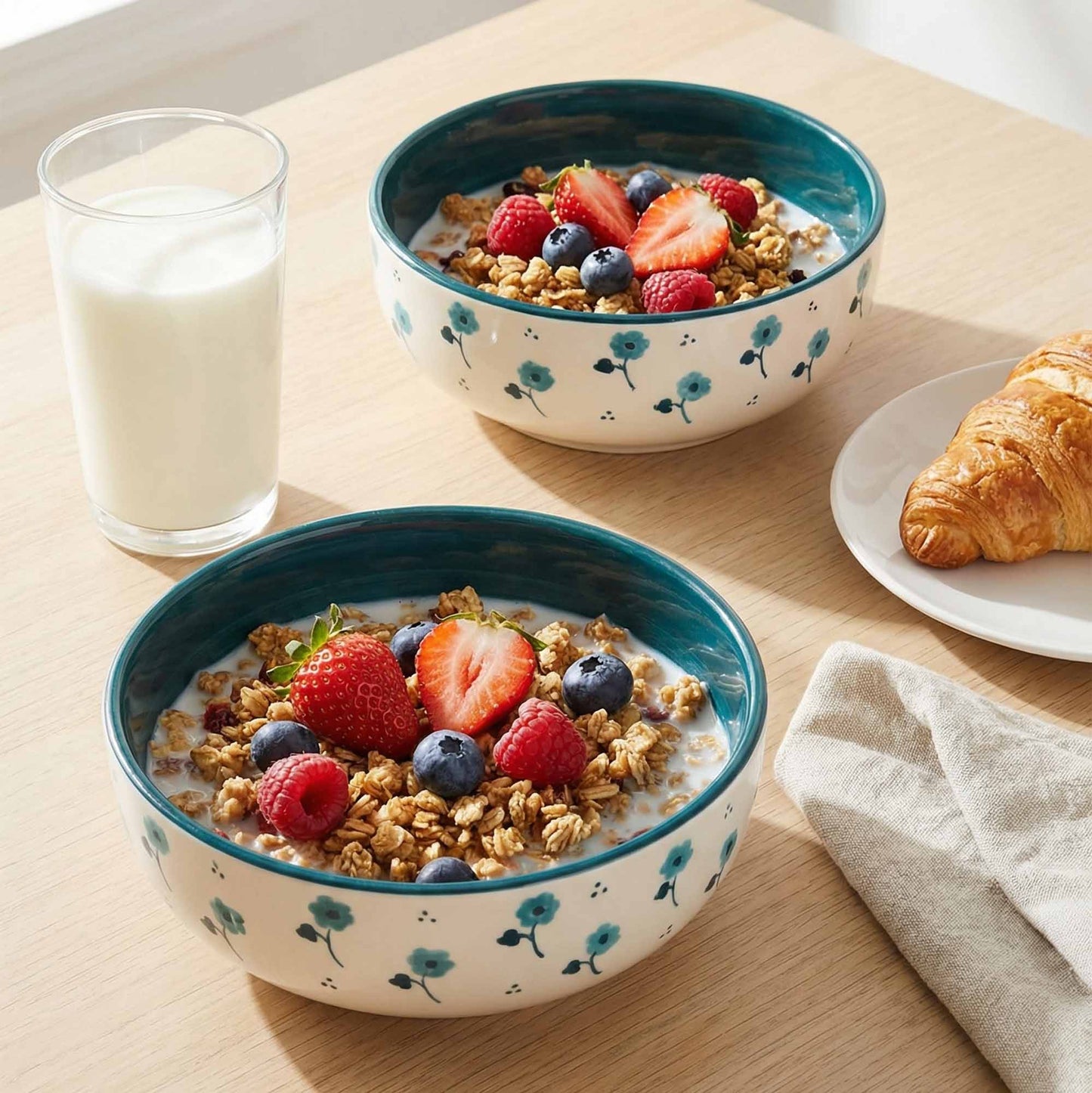 Two bowls of cereal with berries and a glass of milk on a wooden table.