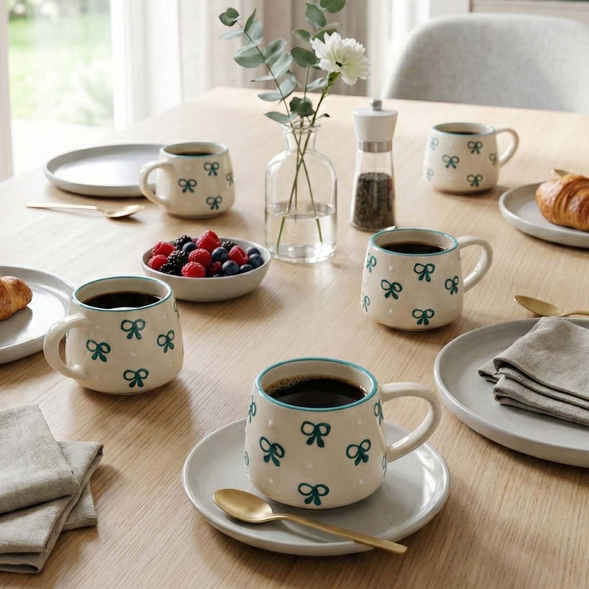 Table setting with coffee mugs, plates, and a bowl of berries.
