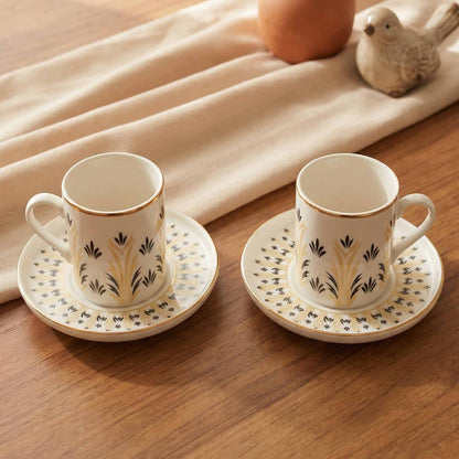 Two porcelain cups with saucers on a wooden table