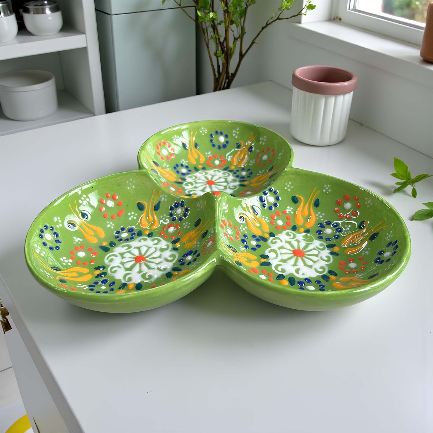 Green ceramic serving tray with floral patterns on a white surface.
