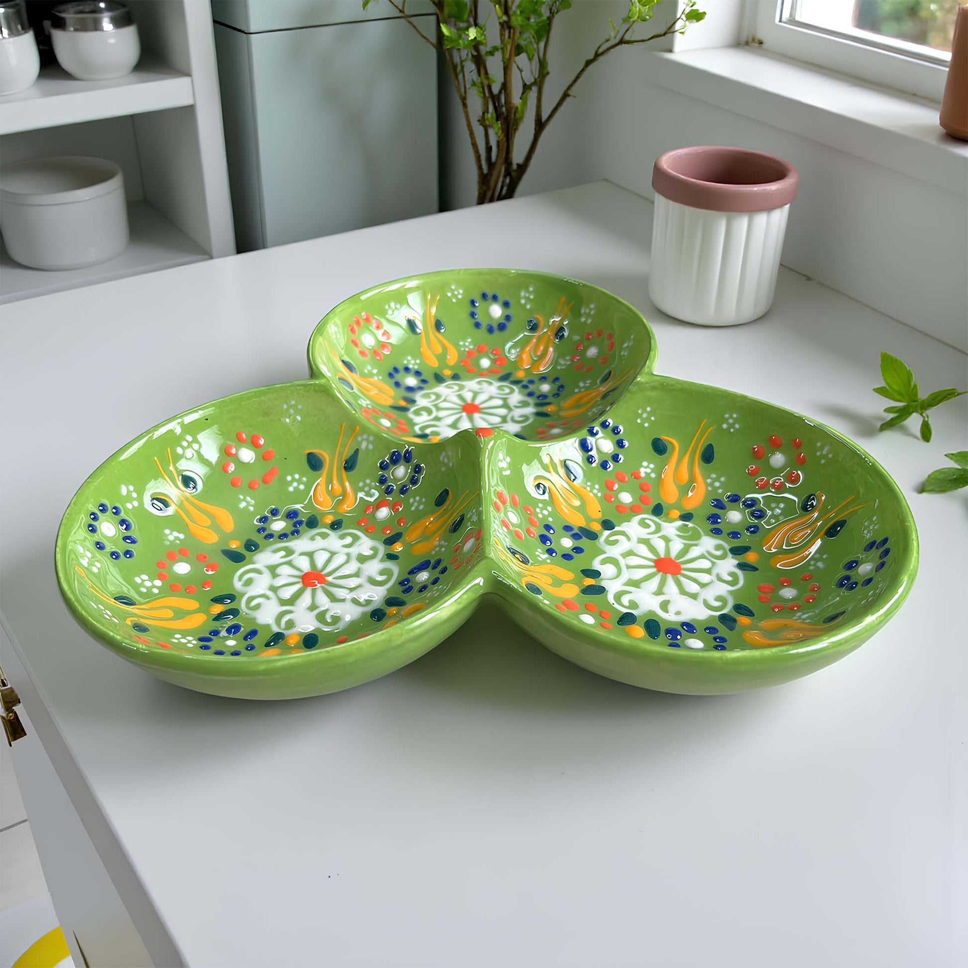 Green ceramic serving tray with floral patterns on a white surface.