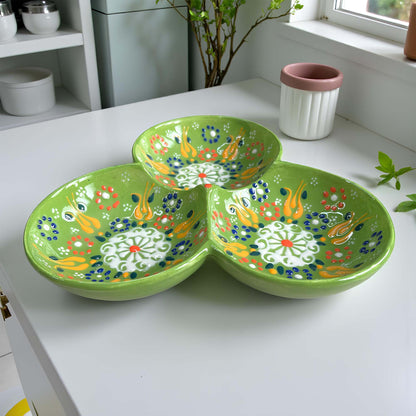 Green ceramic serving tray with floral patterns on a white surface.